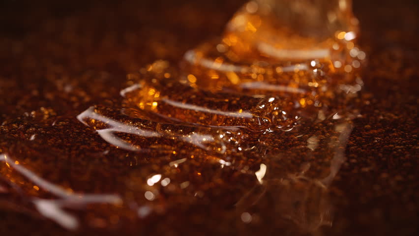Close-up slow motion shot of pouring yellow caramel or fresh honey, seamless dripping sweet liquid syrup drip flows, thick organic honey dripping, golden caramel sauce flowing waves
