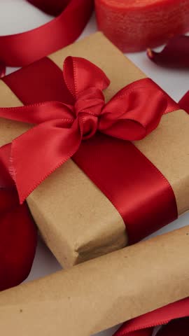 Present for St. Valentine's Day rotating against red festive background. Gift box with red ribbon bow for Birthday, Christmas or Valentines Day, close up. Vertical video