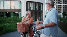 Senior couple enjoying hot summer in the city, going on bike ride around the city, drinking juice from bottle to refresh. Staycation concept. - Powered by Shutterstock - Get 15% off with code: PIKWIZARD15