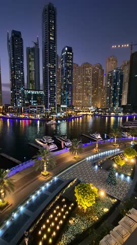 Panoramic view of Dubai Marina promenade at night. Night illumination with flashing lights, United Arab Emirates. Vertical video. High quality 4k footage
