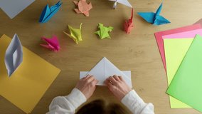 Woman's hands folding origami colored paper on table. Hobby, handmade and decor concept. - Powered by Shutterstock - Get 15% off with code: PIKWIZARD15