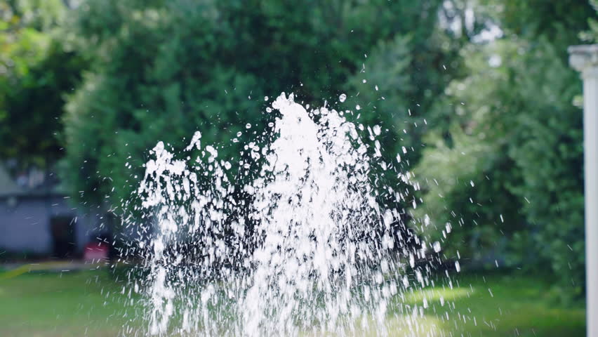 Man refreshing face with cold pool waterfall, relax in swimming pool on summer vacation, water stream wetting male face, waterfall splashes refreshing during hot summer days