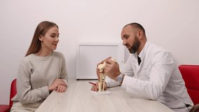 Orthopedic doctor, patient care, knee pain. Medical professional demonstrates knee anatomy using model while consulting with female patient in clinical setting. - Powered by Shutterstock - Get 15% off with code: PIKWIZARD15