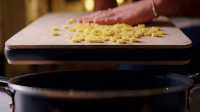 Chef in the kitchen pours animal-shaped pasta into a pot of boiling water. Cooking kids pasta in boiling water. Pour the pasta from the wooden chopper into the pot. Anamorphic lens look. - Powered by Shutterstock - Get 15% off with code: PIKWIZARD15