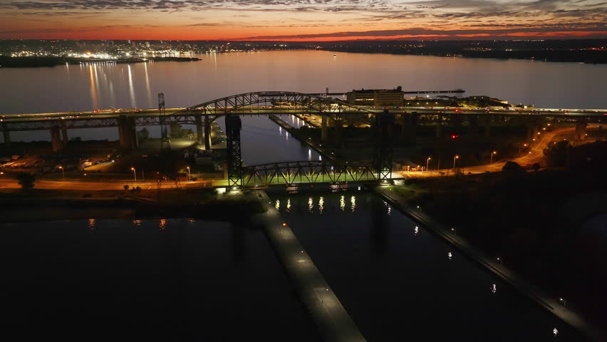 Burlington Skyway Bridge at sunset over calm waters with city lights twinkling