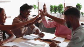 Group of multiethnic students sit at table engage in effective teamwork, give celebratory high-five, gesture of achievement in study, share excellent results and success, completing joint task. Unity - Powered by Shutterstock - Get 15% off with code: PIKWIZARD15