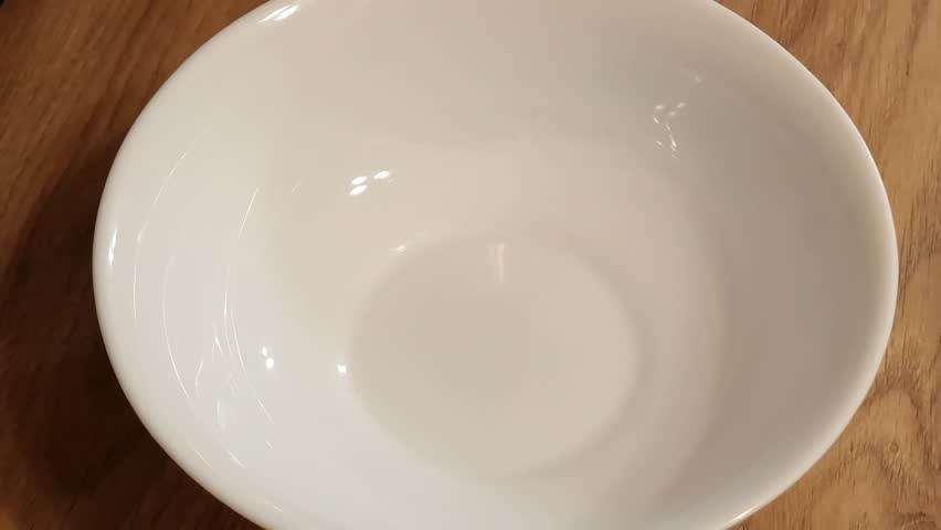 Flax seeds falling into a white bowl. Healthy nutrition, dieting concepts