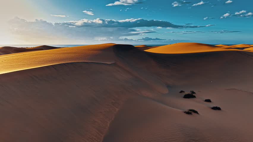 Soaring above the golden sand dunes of Gran Canaria, the breathtaking landscape reveals vibrant colors under a clear blue sky, showcasing the island