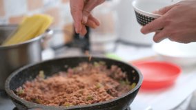 Cooking pasta bolognese at home. Male cooking tasty pasta tomato sauce in kitchen add spices, traditional Italian food, man preparing dinner - Powered by Shutterstock - Get 15% off with code: PIKWIZARD15