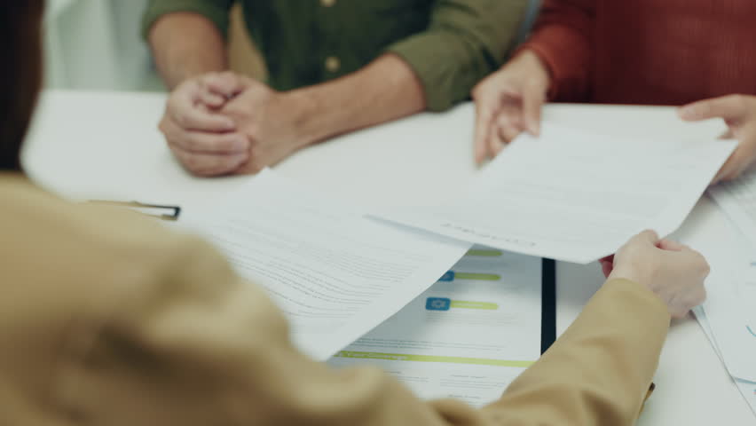 Asian couple examines important documents closely, collaborating on financial and insurance planning in a professional setting with an advisor.