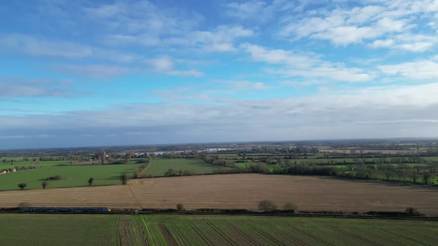 A 4K aerial drone video showcasing a train moving through the Norfolk countryside in England. The clip captures farmland, rural villages, and natural beauty, highlighting the charm of English trains.