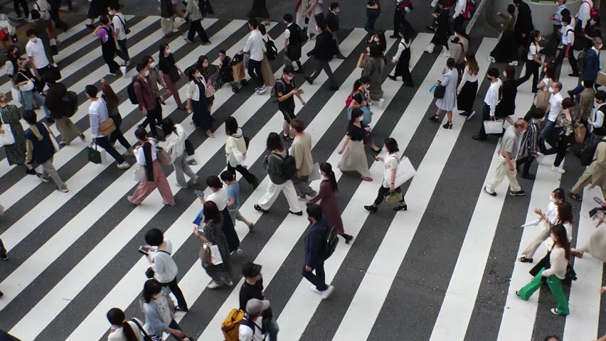 OSAKA, JAPAN : Aerial high angle view of crowd of people walking at zebra crossing near Osaka station in daytime. Commuters at busy rush hour. Japanese lifestyle and business concept. Time lapse shot.