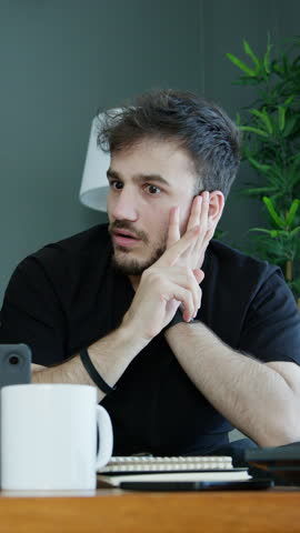 Vertical video. Two men are collaborating on a project in a modern living room. Suddenly, the man on the right has an inspiring idea, sparking their discussion.