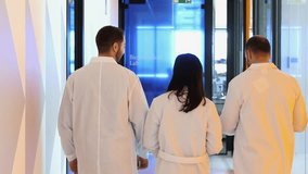 Research team members in white coats walk down corridor of modern laboratory, discussing project details and exchanging professional opinions - Powered by Shutterstock - Get 15% off with code: PIKWIZARD15