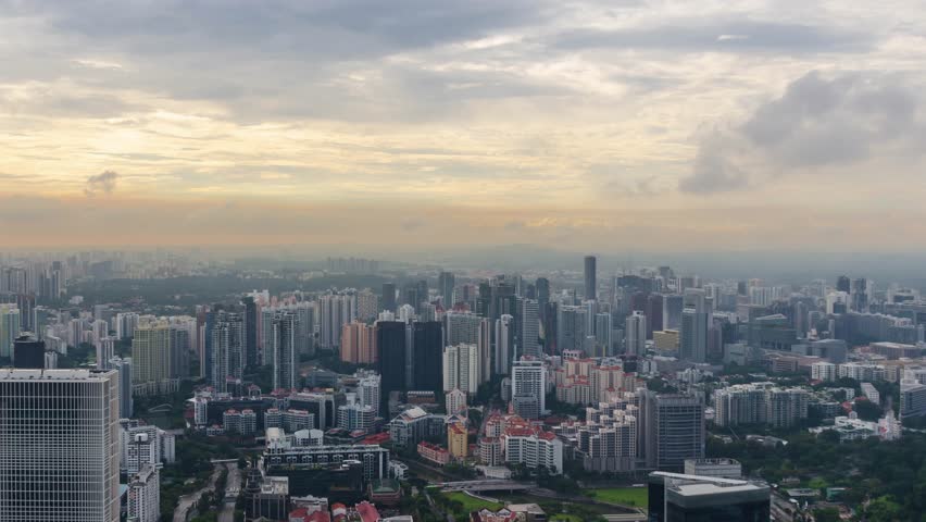 aerial timelapse landscpe view of Singapore city skyline in sunset time with many highrise skyscrapper office and housing building and cloud moving in the sky