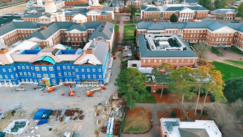 Shifting laterally across the sky, previewing the construction and development of an educational college campus building as equipment can be seen stretched out across the site