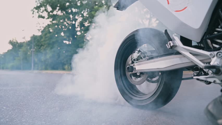 Motorcyclist doing tire burnout. Slow motion. Close-up of a spinning wheel.