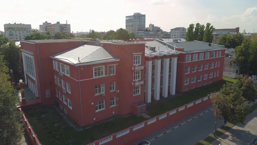 The main building of the Polytechnic Institute in Nizhny Novgorod. The building is Soviet-built, red in color, with beautiful statues standing on the roof. Shooting in summer, on a sunny day.