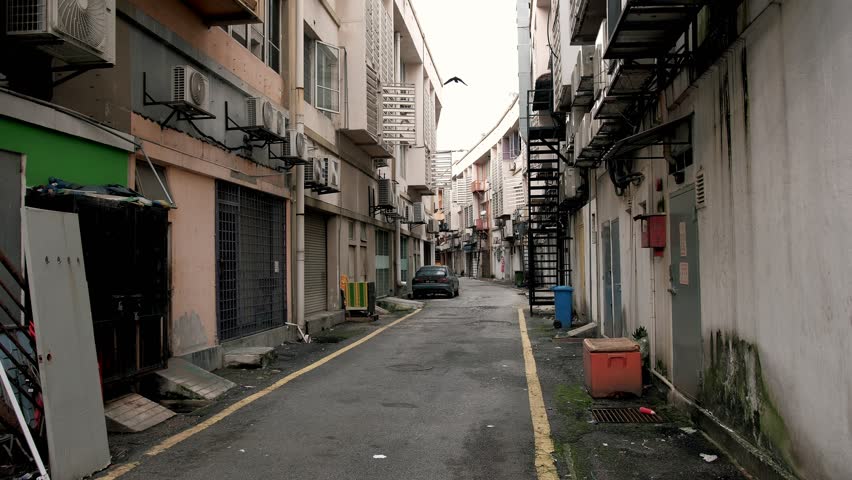 Urban back alley revealing parked vehicle near overflowing trash containers, embodying eerie sense of urban neglect and abandonment. Malaysia, Kuala lumpur