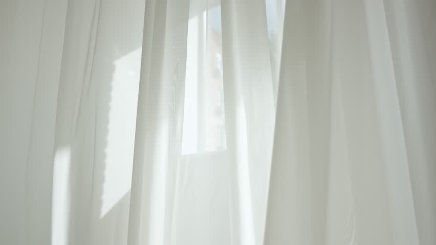 Transparent white silk soft fabrics floating from an open window with sunlight shining through the open window, shadows reflected on textile.