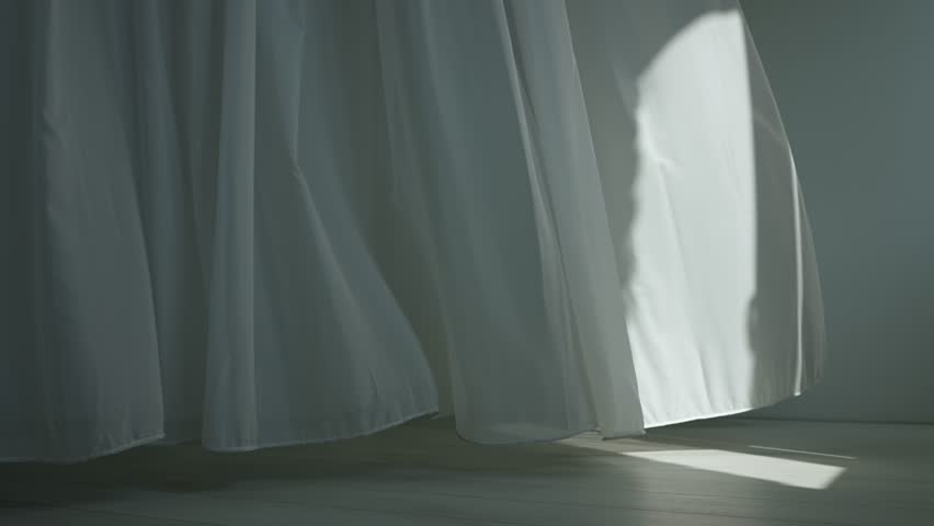 Transparent white silk soft fabrics floating from an open window, sunlight shines through, shadows reflected on textile and floor, full shot.