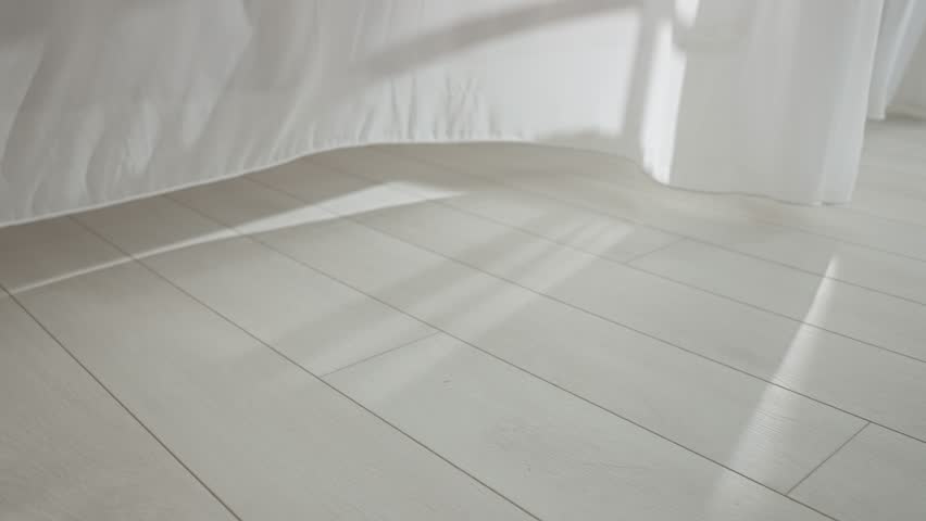 Transparent white silk soft fabrics floating from an open window with light shining through, window door silhouette reflected on the floor.