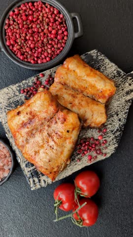 Grilled fish fillet with salt, spices and herbs on dark concrete background