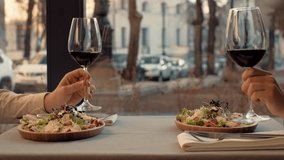 Two diners raise their glasses of red wine in a toast while enjoying fresh salads at a charming restaurant. The warm atmosphere enhances their intimate moment during dinner. - Powered by Shutterstock - Get 15% off with code: PIKWIZARD15