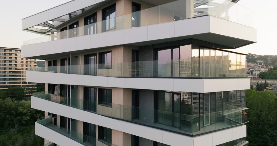 Aerial view building exterior slide up new house city apartment building facade close up, windows, balconies, scaffolding in sunset background. Skyscraper Building in Process. Rent Varna, Bulgaria