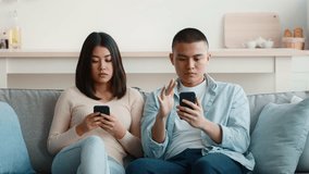Inside a cozy living room, a woman expresses concern while speaking to a man who is focused on his smartphone. The atmosphere suggests a meaningful conversation or disagreement. - Powered by Shutterstock - Get 15% off with code: PIKWIZARD15