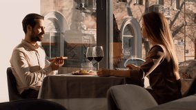 A man and woman share an intimate dinner at a restaurant, illuminated by warm sunlight filtering through large windows. They are engaged in conversation, enjoying fine dining and wine. - Powered by Shutterstock - Get 15% off with code: PIKWIZARD15