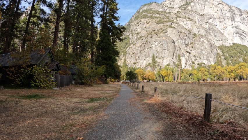 Yosemite Valley bike path rear view passing meadows, cliffs and cabins in Yosemite National Park California.