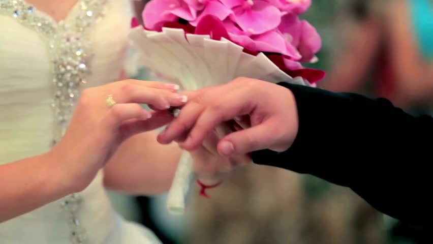 Groom placing the wedding ring on his bride during their wedding ceremony. Young man putting matrimony ring on woman finger. beautiful background