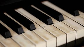 Pianist plays gentle classical music on a beautiful grand piano with one hand close-up in slow motion. Piano keys close up in dark colors. - Powered by Shutterstock - Get 15% off with code: PIKWIZARD15