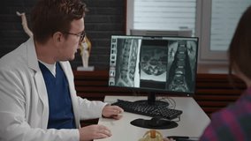 An experienced doctor, osteopath, conducts consultations in a modern clinic. A man consults a patient. The MRI image is open on the computer screen. - Powered by Shutterstock - Get 15% off with code: PIKWIZARD15