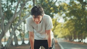 Tired runner asian man breathing after run marathon in public park. Young male athlete have break after running exercise in summer park. Sport man resting after workout outdoor. - Powered by Shutterstock - Get 15% off with code: PIKWIZARD15
