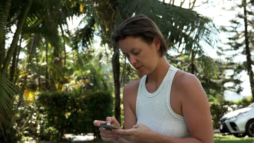 Woman Enjoying Nature While Using Smartphone in Tropical Setting
