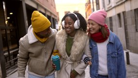 Young multi ethnic friends are enjoying a winter day together, walking arm in arm through a city street - Powered by Shutterstock - Get 15% off with code: PIKWIZARD15
