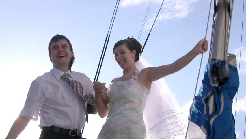 Happy young groom (in white shirt and tie) and his bride (in white wedding dress