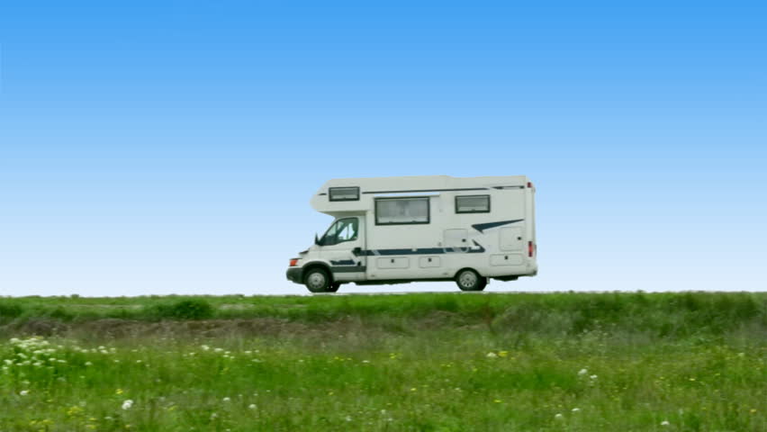 The camper leaves on road on a background of steppe grasses and the blue sky