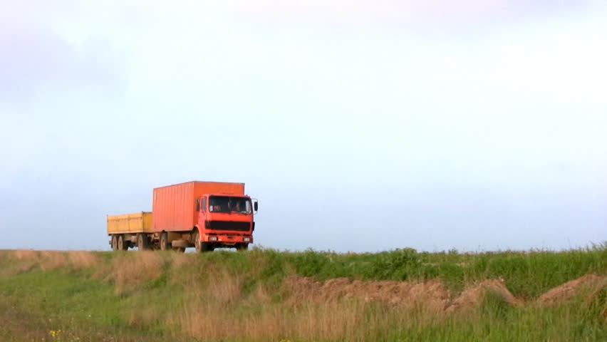 Big orange truck with a trailer passed and left on the steppe highway against