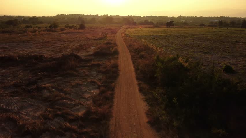 Country road through pasture. Sunrise over a dirt road. Dusty rural road landscape and a beautiful sunset sky use for natural background.