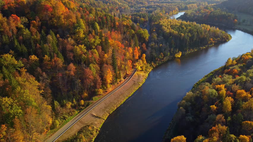 Aerial shot of Sigulda's Gauja River in autumn, vibrant forests and scenic road