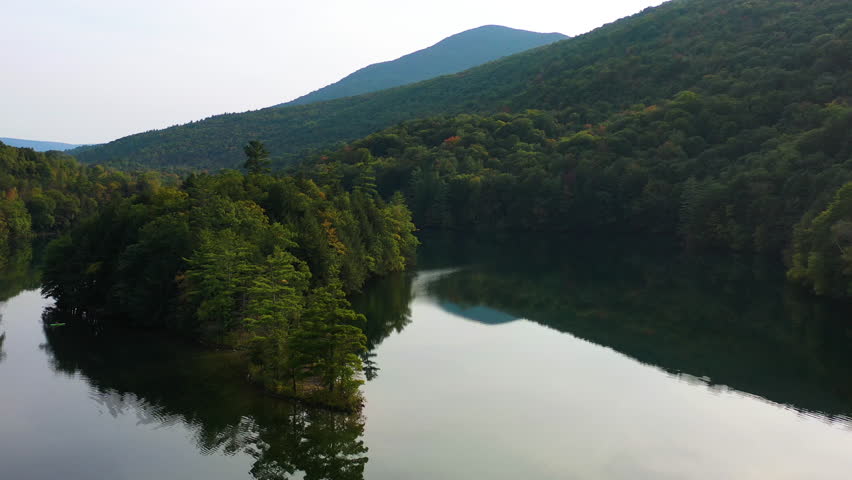 Aerial view over a lake in middle of forest and mountains, fall in Vermont, USA