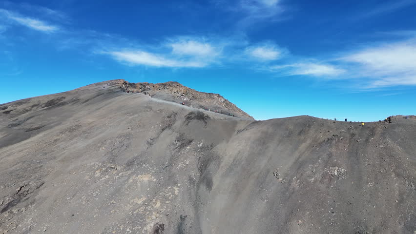 Aerial shot of Uhuru Peak under a vibrant African sky on Mount Kilimanjaro, rotating drone shot