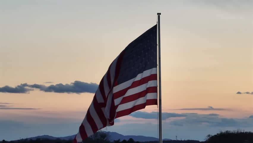 Waving flag of United States America at golden sunrise sky. Aerial orbit shot. Proud and pride nation of USA. Close up shot.