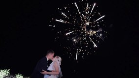 Fireworks at wedding of a young couple. The newlyweds kiss during the explosions of fireworks in night sky and continue to watch beautiful powerful fireworks. The concept of celebrating a wedding day - Powered by Shutterstock - Get 15% off with code: PIKWIZARD15