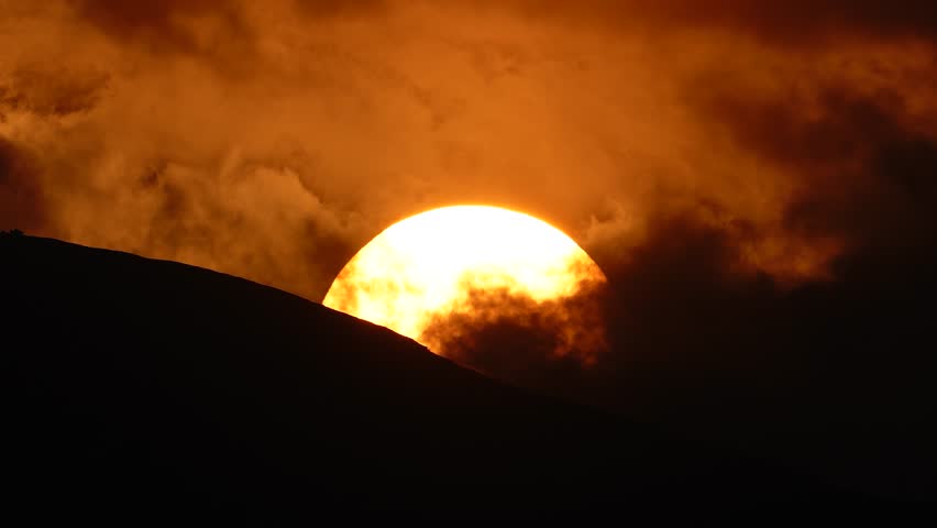 Timelapse of sunset with clouds covering the sun over the mountains in India.