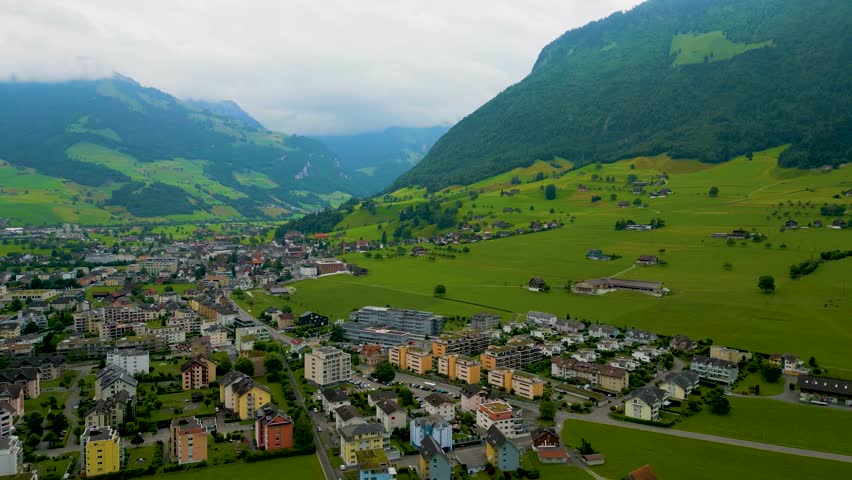 4K Drone Video of Passenger Train Passing Through a Scenic Village at the base of Stanserhorn Mountain in Stans, Switzerland