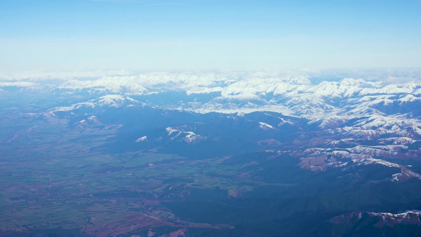 Airplane flight from Christchurch to Auckland over the snowcapped Southern Alps in New Zealand. Drone wide shot.